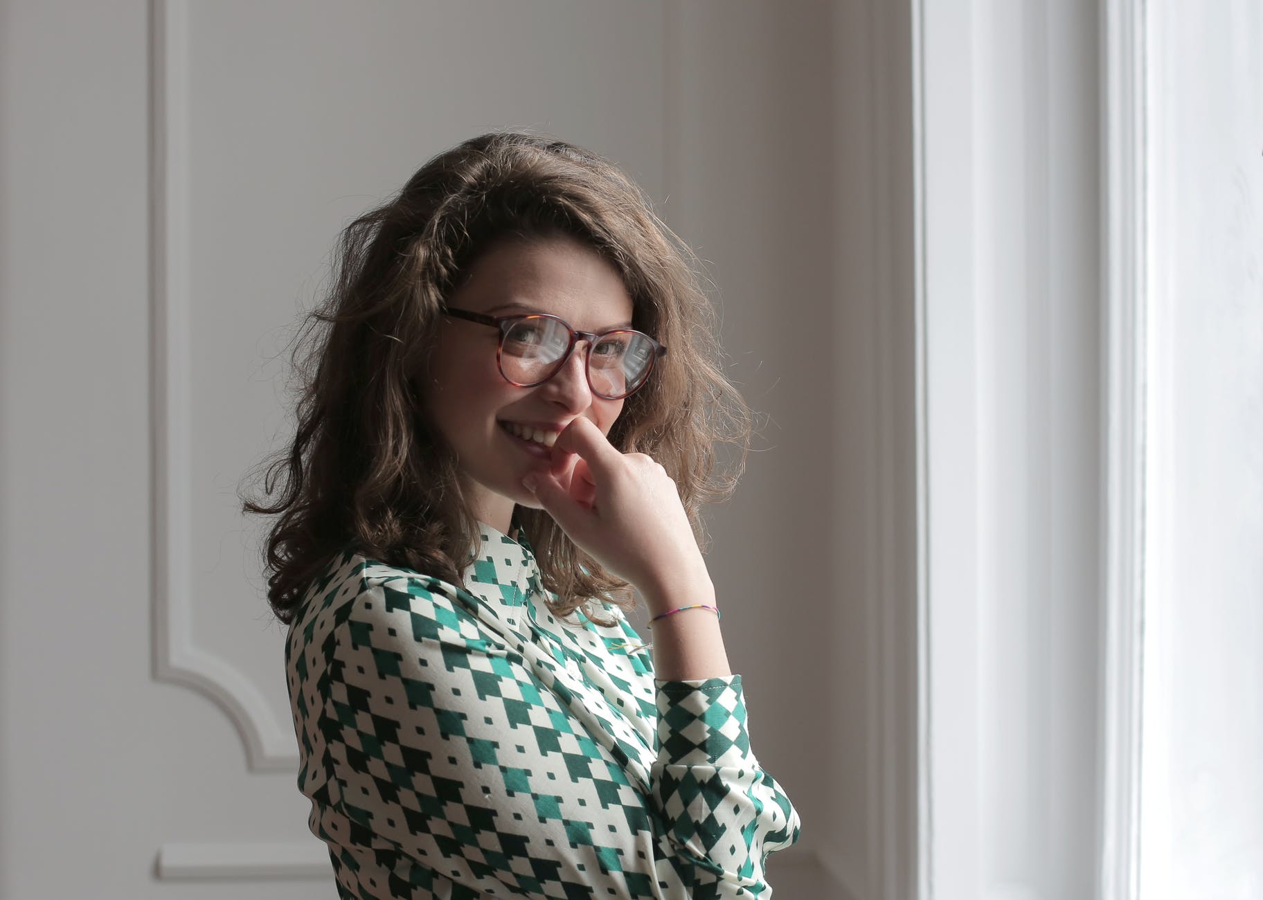 happy woman in eyeglasses standing in apartment room